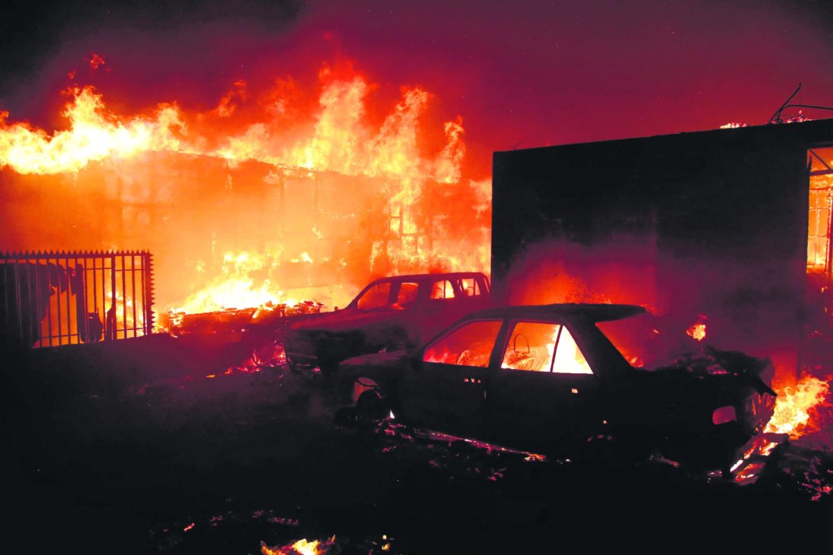 An image from The Daily Guardian of the Chile wildfires reaching a city, burning buildings and cars.
